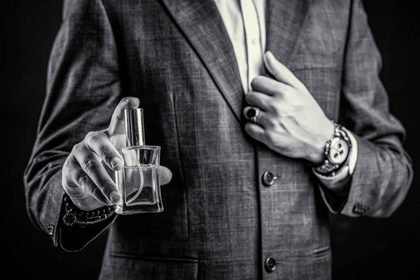 香水やケルンボトルや香水、化粧品、香りのケルンボトル、男性はケルンを保持します。瓶の香水を持っている男性。ビジネススーツの手首の時計を手に入れます。黒と白 - 写真・画像