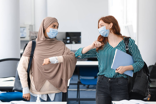 Diverses étudiantes portant des masques visage saluant et cognant les coudes - Photo, image