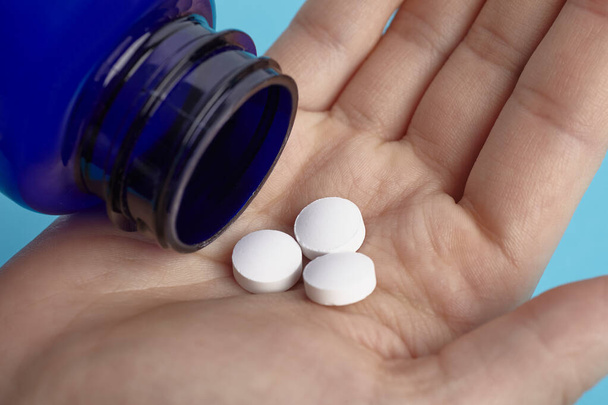 Weiße Tabletten quellen auf einer Hand aus der Verpackung. Haufen Pillen - medizinischer Hintergrund - Foto, Bild
