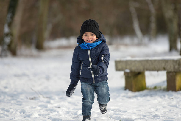 młody chłopiec bawiący się pod śniegiem - Zdjęcie, obraz