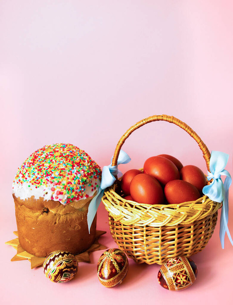 Pastel de Pascua, una canasta de mimbre decorada con cintas azules con huevos de Pascua marrones y huevos pintados a mano sobre un fondo rosa pastel. Tarjeta de felicitación de Pascua. Copiar espacio. - Foto, Imagen