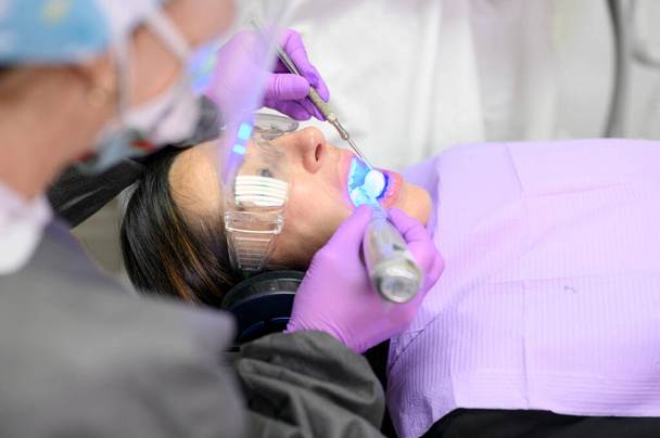Mujer joven recibiendo luz ultravioleta para el procedimiento de blanqueamiento en el consultorio del dentista - Foto, imagen