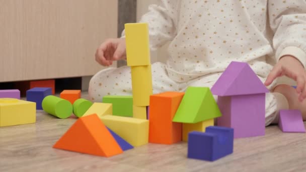 Ребенок играет с цветными кубиками в детской комнате на полу. Парень строит семейный дом. Образовательные игры для развития детей. Обучение ребенка через игру. Счастливая семья, дочь - Кадры, видео