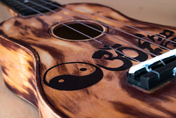 Close-up de um ukulele lixado e pintado em Ontário, Canadá, fundo marrom, 2021. - Foto, Imagem