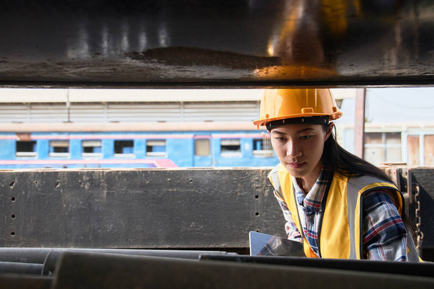 Lagermitarbeiter mit gelber Weste und Helm, in der Hand ein Tablet, kontrollieren Outdoor-Waren. - Foto, Bild