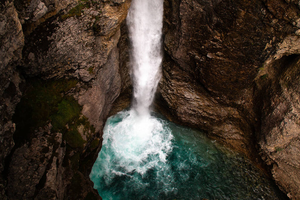 ムーディの画像は、カナダのアルバータ州バンフ近くの夏のジョンストンキャニオンアッパーフォールズハイキングで撮影されました。滝の底にあるターコイズブルーの水は、カナダ旅行のための人気のある観光スポットです。.  - 写真・画像
