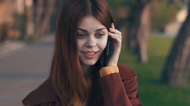 mooie vrouw buiten praten aan de telefoon in het park - Foto, afbeelding