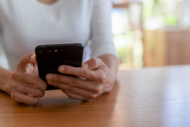 Lähikuva käsissä kaunis nuori nainen kädessään mobiili, älypuhelin istuu kahvilassa. Pehmeä keskittyä kädet naisten tilalla ja käyttää matkapuhelinta kahvilassa. Tekniikan ja elämäntavan käsite. - Valokuva, kuva