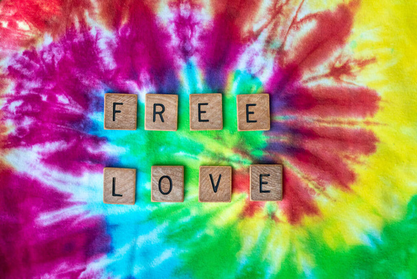 Toronto, Ontario, Canadá 'Free love' deletreado en letras de madera en tela de tinte de lazo de patrón de remolino multicolor, para el Día de San Valentín 2021. - Foto, Imagen