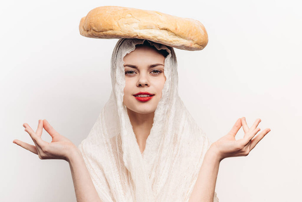 érzelmes nő átlátszó ruhával, kerek kenyérrel a fején, kezével integetve meditációval. - Fotó, kép
