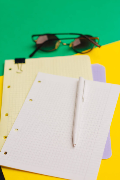 egy csésze kávé színes háttérrel és papírlapokkal jegyzettömb irodai szemüveg - Fotó, kép