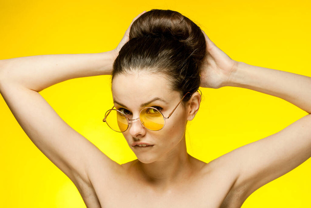 顔の近くに裸の肩の黄色いメガネの手を持つ女性明確な肌 - 写真・画像