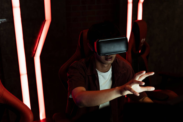 Εκπληκτική εμπειρία εικονικής πραγματικότητας. Ασιάτης που χρησιμοποιεί VR για να παίξει το παιχνίδι για πρώτη φορά, φτάνοντας το χέρι για να αγγίξει κάτι. - Φωτογραφία, εικόνα