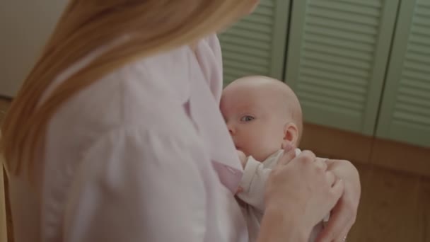 Hoge hoek schot van aanhankelijke moeder strelen baby dochter terwijl borstvoeding haar thuis - Video