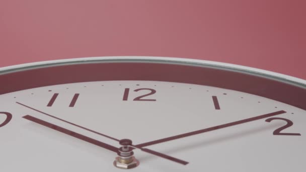 閉じると、白い壁の時計は時間の経過を示しています。短い手と長い手は、時間を移動するために働いている。ピンクの背景に. - 映像、動画