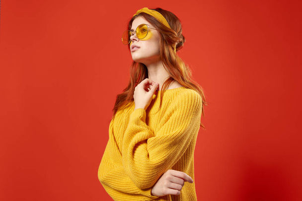 きれいな女性は眼鏡をかけて黄色のセーター感情カジュアルな着用赤の背景 - 写真・画像