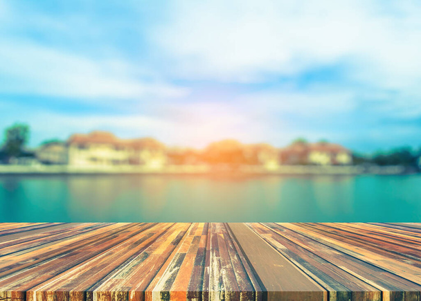Wood pier or an old wooden table with vintage tone blur image of lake and sunset sky in background - Photo, Image