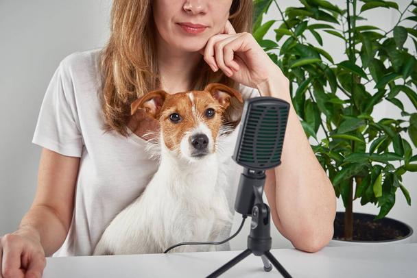 Egy nő podcastet vesz fel egy kutyával. Távmunka otthon. Állatgondozás - Fotó, kép