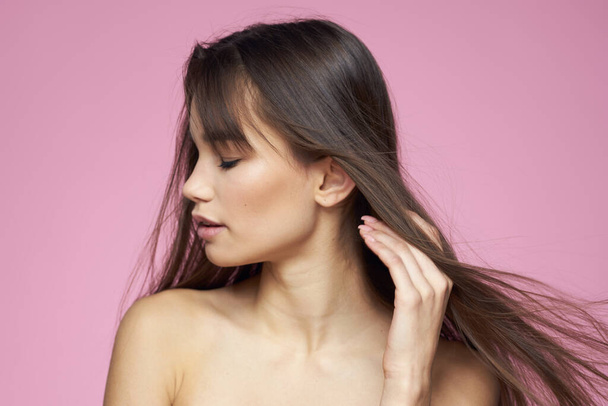 brunette kale schouders heldere huid lichaamsverzorging roze achtergrond - Foto, afbeelding