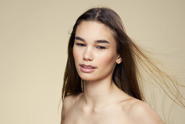 Pretty woman naked shoulders cosmetics clean skin hair care beige background - Fotoğraf, Görsel