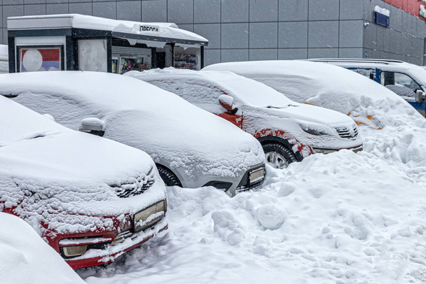 A parkolóban parkoló autókat hó borította egy nagy hóvihar után. Havas téli időjárás a városban - Fotó, kép