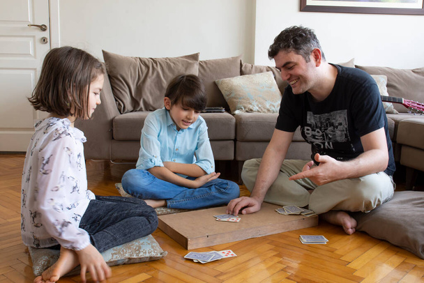 Isä ja lapset pelaavat ja oppivat korttipelejä.  - Valokuva, kuva