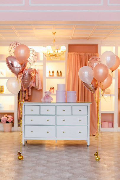 Garderobe, Garderobe, Kleiderständer in rosa und pfirsichfarben mit Luftballons. - Foto, Bild