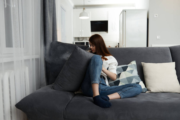 жінка комфортно поселилася на дивані в інтер'єрі відпочинку в квартирі
 - Фото, зображення