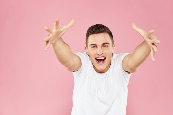 Homem emocional gesticulando com as mãos branco t-shirt rosa isolado fundo - Foto, Imagem
