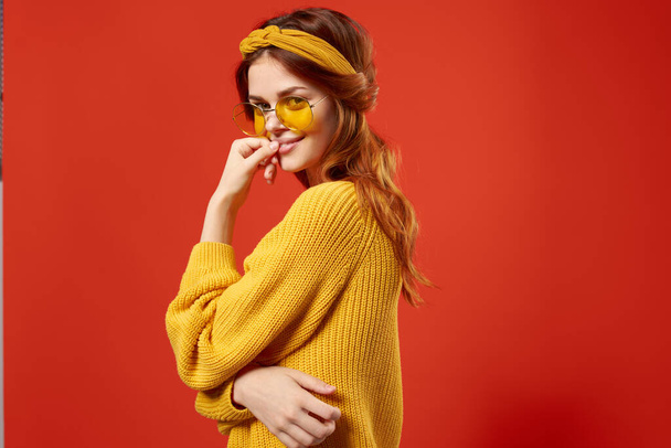 Neşeli kadın hippi sarı süveter gözlüğü duyguları kırmızı arka plan - Fotoğraf, Görsel