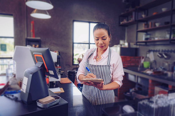  Portret van zelfverzekerde vrouwelijke barista die achter de toonbank staat. Vrouw cafe eigenaar in schort kijken naar camera en glimlachen. - Foto, afbeelding