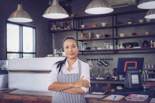  Portrait de femme barista confiante debout derrière le comptoir. Femme propriétaire de café dans tablier regardant la caméra et souriant. - Photo, image