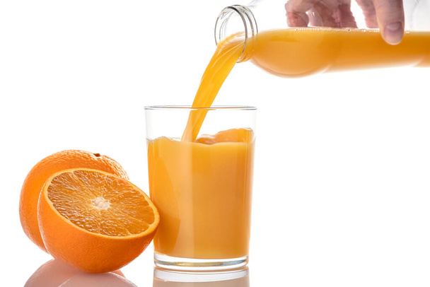Mujer vertiendo jugo de naranja en vidrio, aislado sobre fondo blanco. - Foto, Imagen