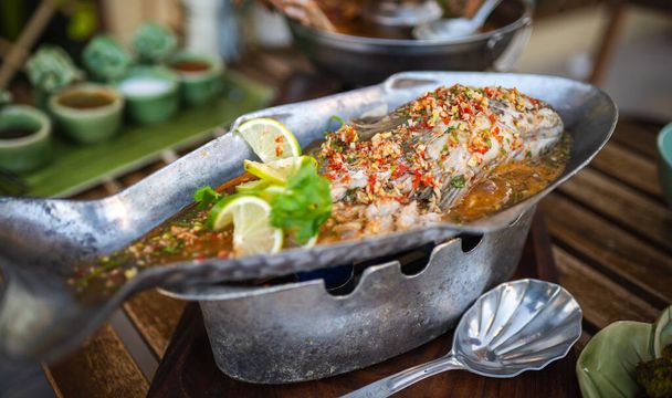 Ψάρι αχνιστό με lime pepper και διάφορα συστατικά τροφίμων σε ένα τραπέζι με ταϊλανδέζικα πιάτα - Φωτογραφία, εικόνα