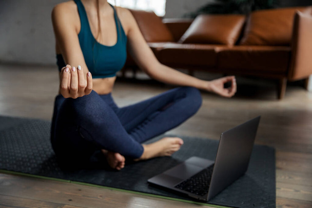 スポーツフィットスリム女性コーチは、オンラインビデオ瞑想スハサナの姿勢を練習します。高品質の写真 - 写真・画像