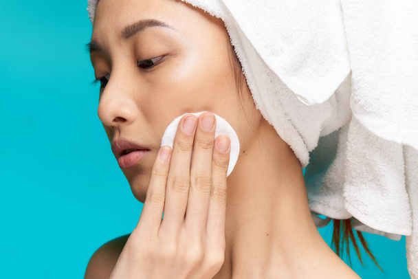 pretty woman towel on head wiping face with cotton pad health blue background - Φωτογραφία, εικόνα