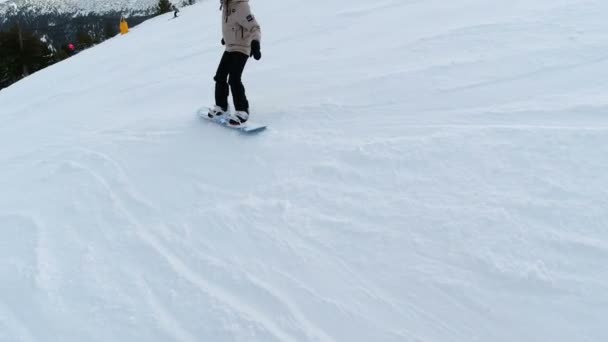 Жінка сноубордистка повертає праворуч і ліворуч на лижному схилі, що падає на гірський схил
 - Кадри, відео