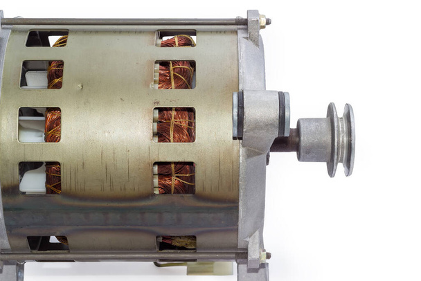 Fragmento de motor eléctrico con polea, bobinado visible en orificios de ventilación en la carcasa y soporte de amortiguador, vista lateral sobre fondo blanco - Foto, Imagen