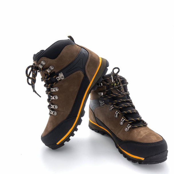 Men's trekking boots with grooved soles. Made in brown nubuck and black vinyl. Yellow finish. Metal fittings, striped laces. Isolated on white - Photo, Image