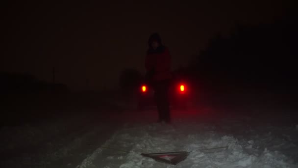 A férfi felállított egy vészleállító táblát a kocsija mellett egy téli éjszakán.. - Felvétel, videó