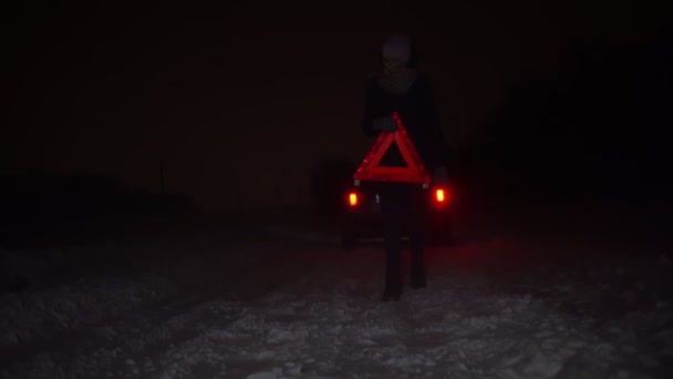 Egy lány felállított egy vészleállító táblát a kocsija mellett egy téli éjszakán.. - Felvétel, videó