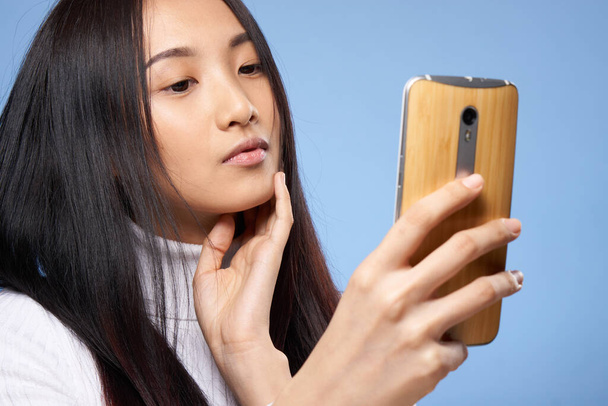 Frau asiatischen Aussehens mit einem Telefon in der Hand Kommunikations-Internet-Technologie - Foto, Bild