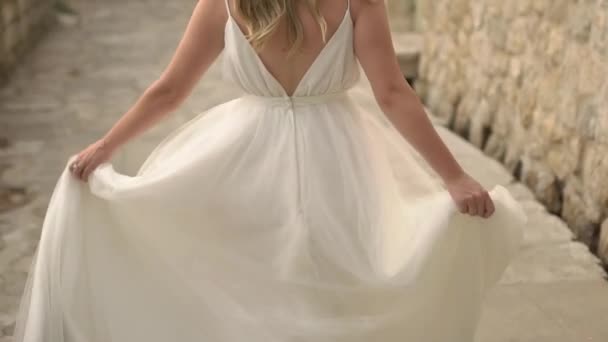 The bride in a delicate dress is spinning on the street of the old city, holding her skirt - Footage, Video