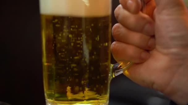 κοντά το χέρι του μπάρμαν κρατώντας ένα ποτήρι στο οποίο η μπύρα χύνεται. Αλκοολούχο ποτό - Πλάνα, βίντεο