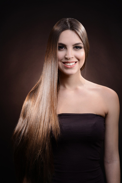 Beautiful young woman with long hair on dark brown background - Foto, Imagem