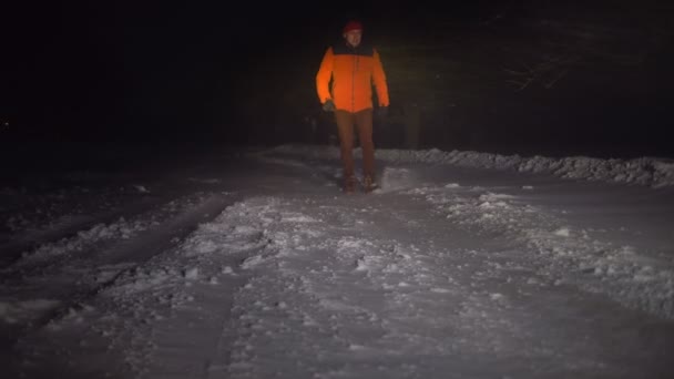 Un hombre camina en la carretera por la noche en un fuerte viento de invierno y ventisca. - Metraje, vídeo