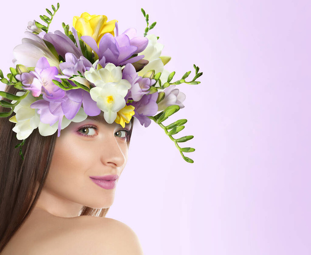 Pretty woman wearing beautiful wreath made of flowers on lilac background, space for text - Foto, afbeelding