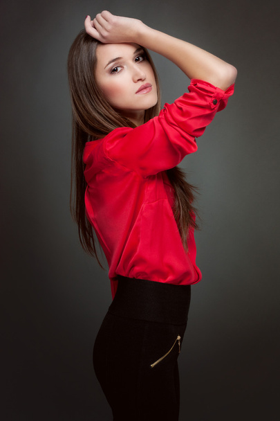 Fashion model in a red blouse and leggings on a dark gray background - Fotoğraf, Görsel