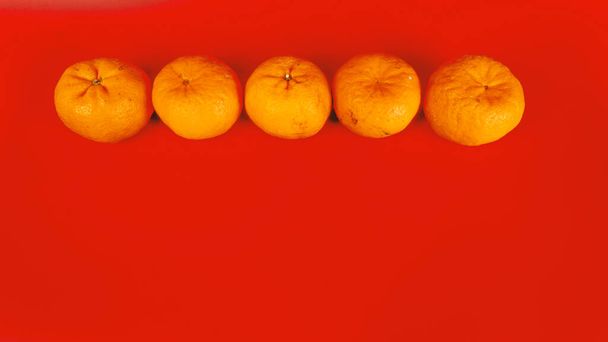 5 oranges mandarines pour la célébration du Nouvel An chinois et la décoration sur fond rouge - Photo, image