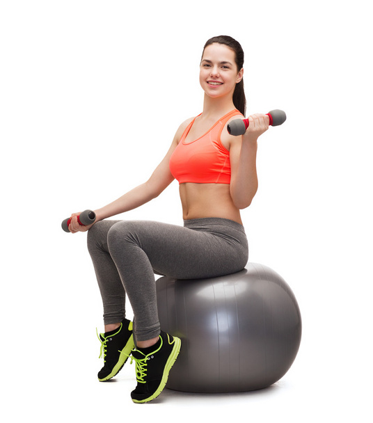 Teenager with dumbbells sitting on fitness ball - Fotó, kép